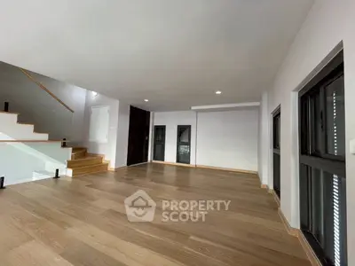 Spacious modern living room with wooden flooring and large windows in a contemporary home.
