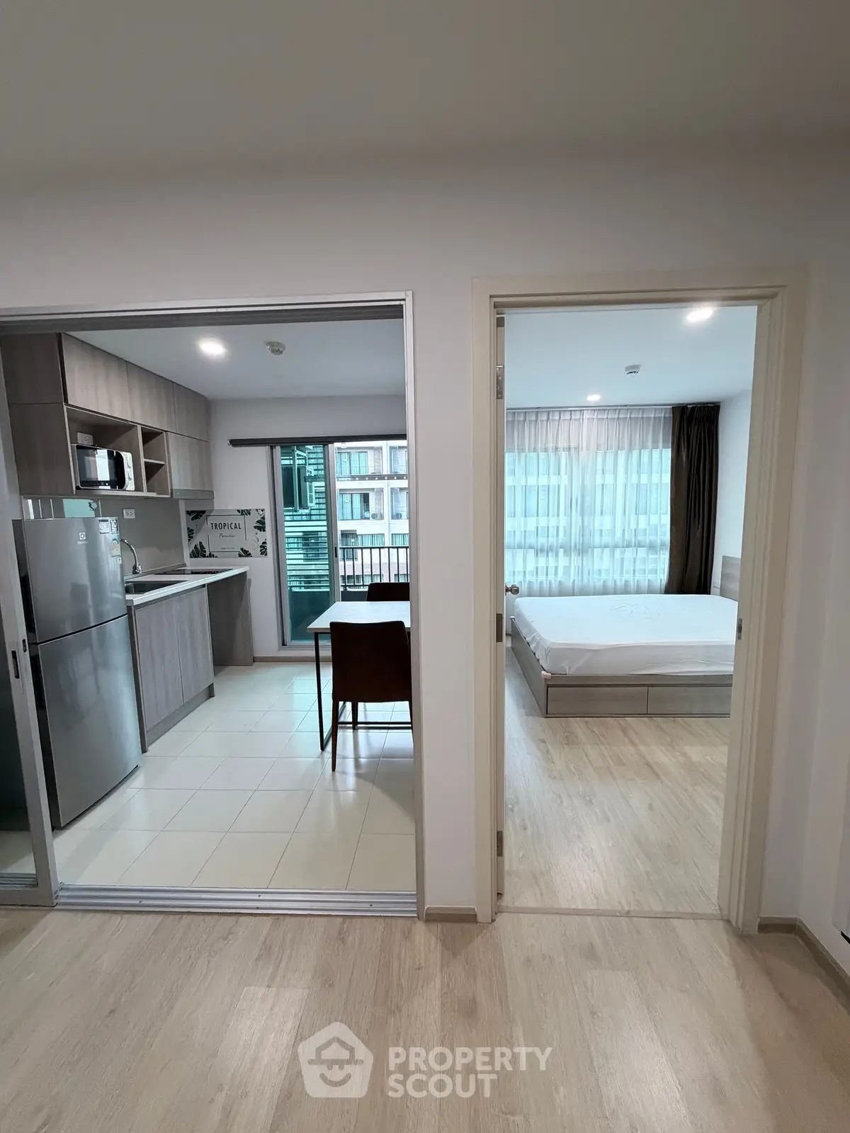 Modern apartment interior with kitchen and bedroom, featuring sleek design and natural light.