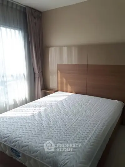 Bright bedroom with large window and modern wooden headboard.