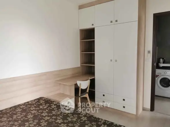 Modern bedroom with built-in wardrobe and study desk, featuring a washing machine in view.
