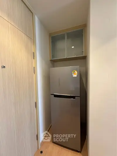 Compact kitchen corner with modern fridge and storage cabinet in cozy apartment.