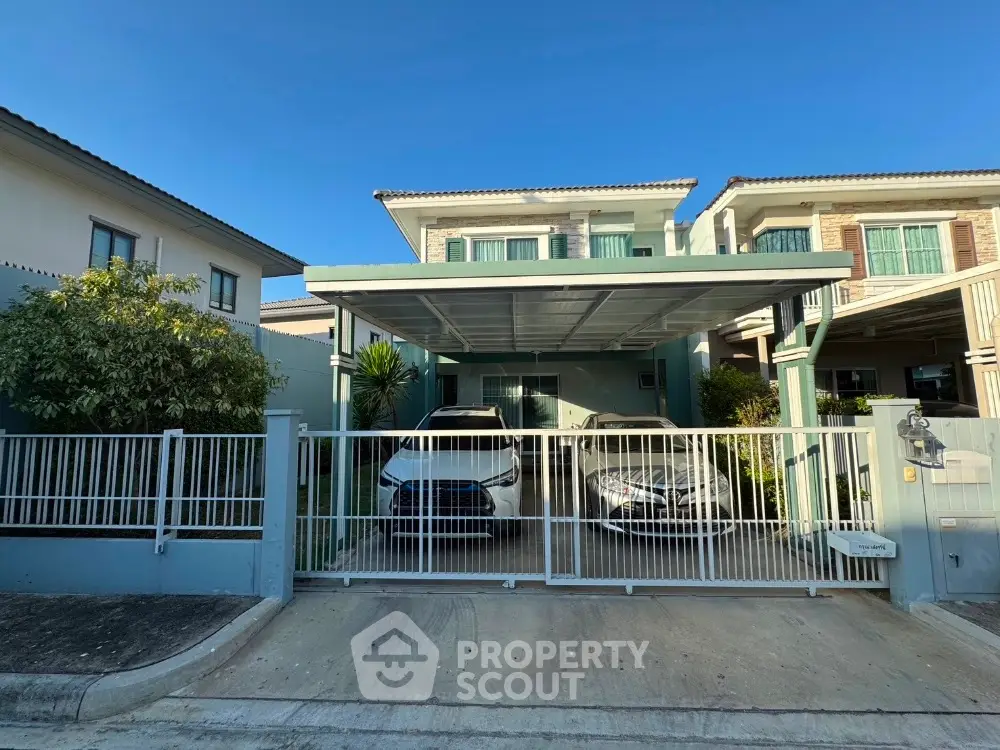 Modern two-story house with carport and gated driveway in suburban neighborhood.