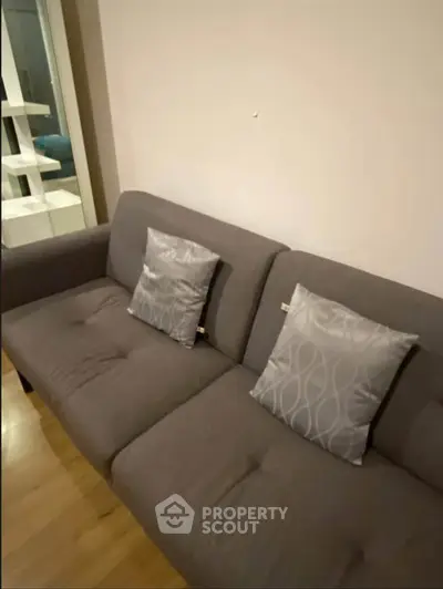 Cozy living room with modern gray sofa and stylish cushions, perfect for relaxation.