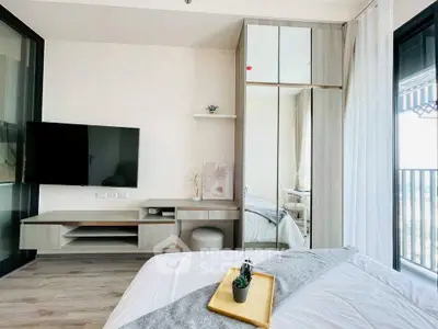Modern bedroom with sleek furniture and balcony view, featuring a mounted TV and mirrored wardrobe.