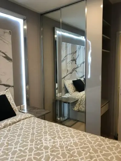 Modern bedroom with stylish decor and mirrored wardrobe in a luxury apartment.
