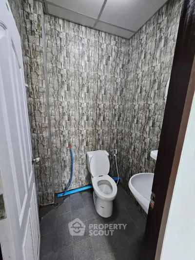 Compact bathroom with modern stone-patterned walls and basic fixtures.