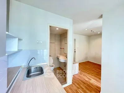 Modern apartment interior with kitchen and bathroom, featuring sleek wooden flooring and minimalist design.