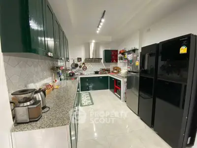Spacious modern kitchen with sleek green cabinets and high-end appliances.