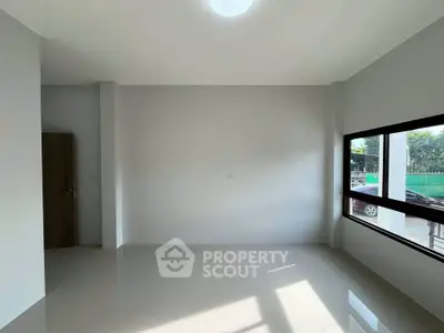 Spacious empty room with large window and natural light, ideal for customization.