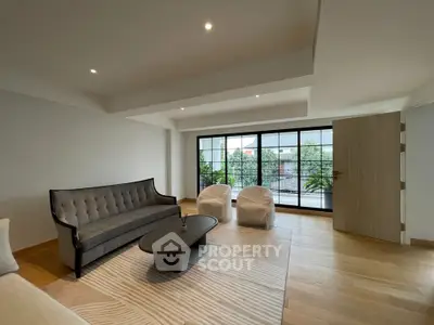 Spacious modern living room with elegant furniture and large windows offering a serene garden view.