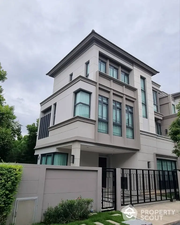 Modern three-story house with sleek design and large windows in a serene neighborhood.