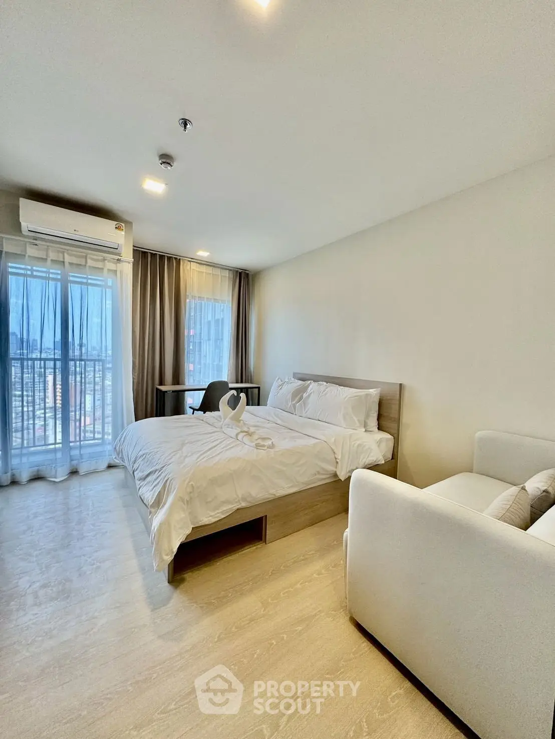 Spacious modern bedroom with city view, featuring cozy bed and elegant decor.