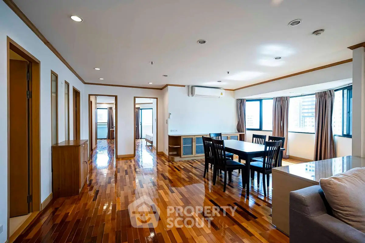 Spacious modern living room with hardwood floors and large windows.