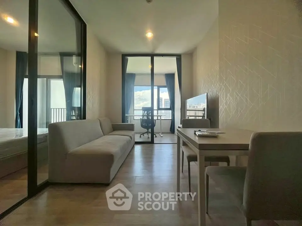 Modern living room with glass partition and city view, featuring sleek furniture and natural light.