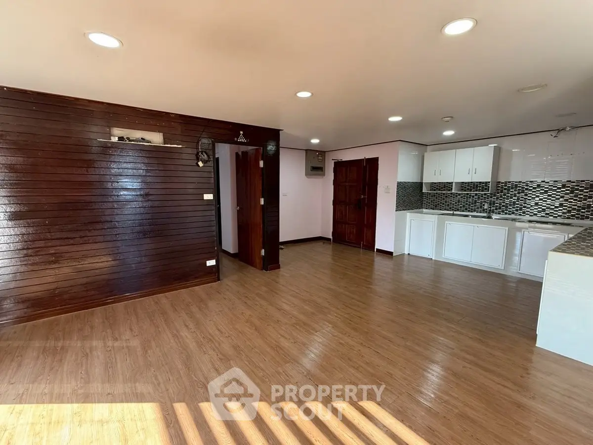 Spacious open-plan living area with wooden flooring and modern kitchen