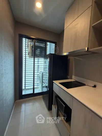 Modern compact kitchen with sleek cabinetry and glass door leading to balcony