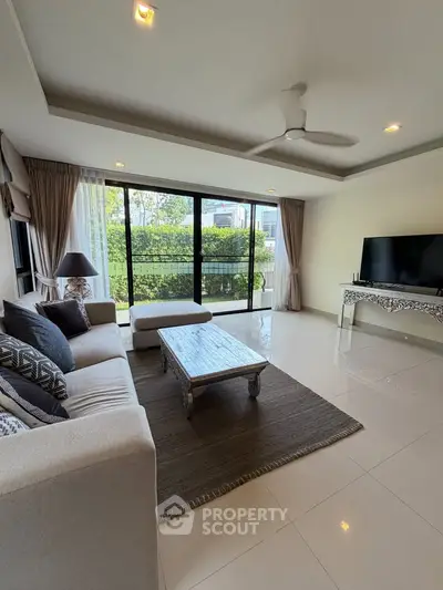 Spacious living room with modern decor and large windows overlooking greenery.