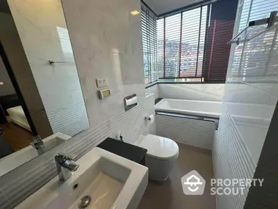 Modern bathroom with city view, featuring sleek fixtures and a bathtub.