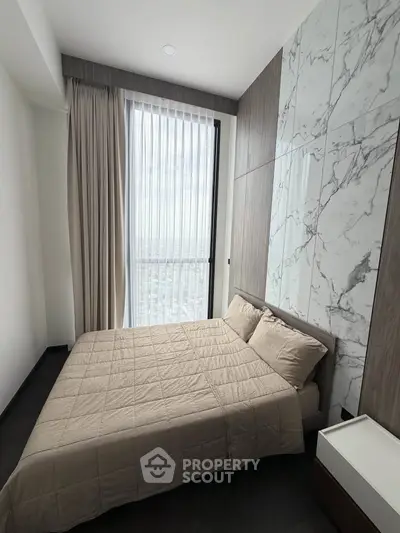 Modern bedroom with marble accent wall and large window offering city views.