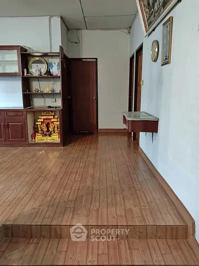 Spacious living room with wooden flooring and built-in shelving unit.