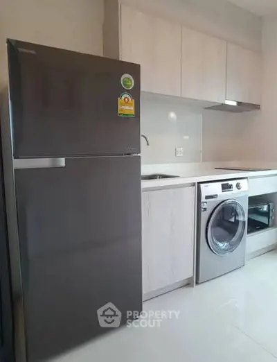 Modern kitchen with sleek appliances including fridge and washing machine.