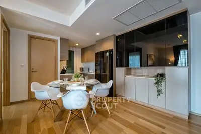 Modern kitchen with open layout and stylish dining area, featuring sleek cabinetry and wooden flooring.