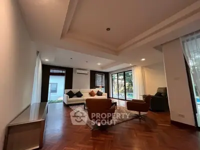 Spacious living room with modern furniture and large windows offering garden views.