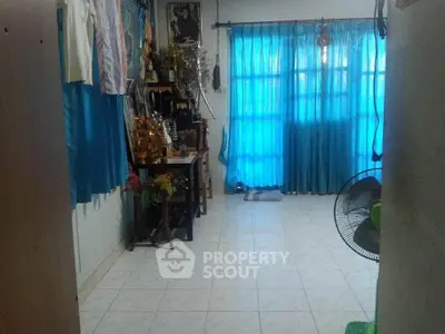 Cozy living room with blue curtains and tiled floor, featuring a fan and decorative items.