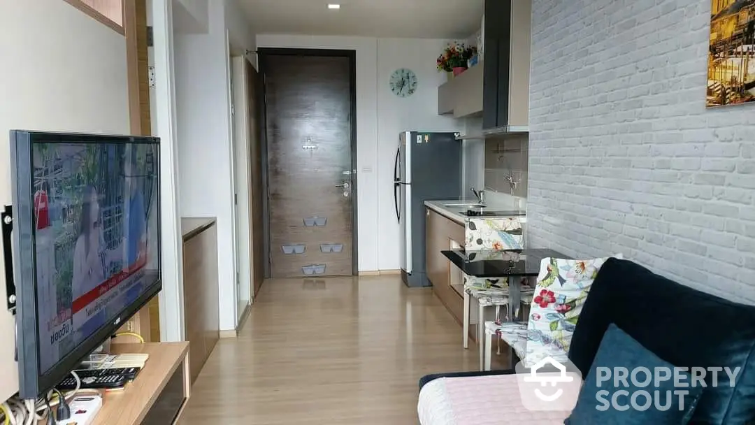 Cozy and modern studio apartment with integrated living space, featuring a sleek kitchenette, comfortable seating area, and stylish brick accent wall.