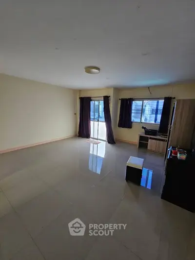 Spacious living room with large windows and modern tile flooring
