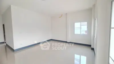 Spacious empty room with glossy tiled floors and large windows, perfect for customization.