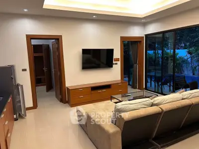 Modern living room with sleek furniture and large glass doors opening to a lush garden view.