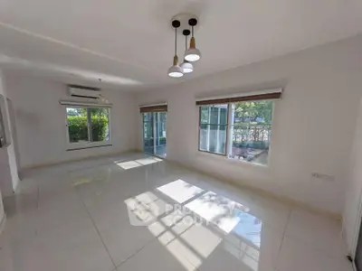 Spacious living room with large windows and modern lighting, offering abundant natural light.