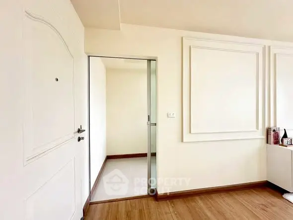 Modern minimalist interior with white walls and wooden flooring, featuring a sleek sliding door.
