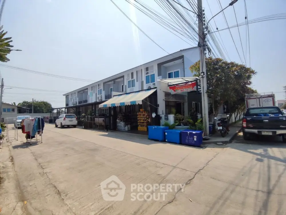 Modern townhouse exterior with street view and parked cars, showcasing urban living.