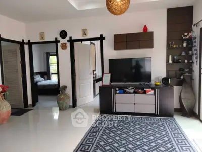 Spacious living room with modern decor and open layout, featuring a large TV and stylish shelving.