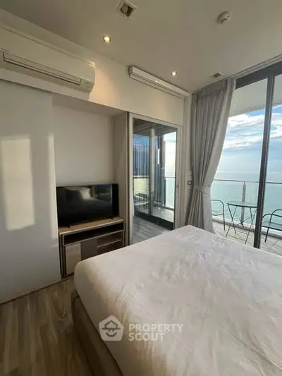 Luxurious bedroom with stunning ocean view and balcony access, featuring modern decor and ample natural light.