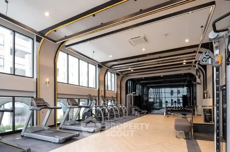Spacious modern gym with state-of-the-art equipment and large windows for natural light.