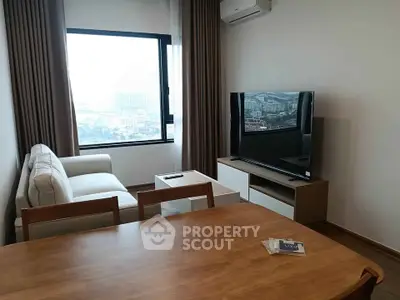 Modern living room with large window and stylish furniture in high-rise apartment.