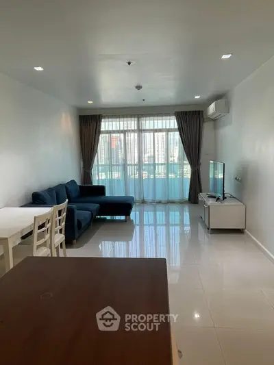 Spacious living room with modern furniture and large windows offering city views.