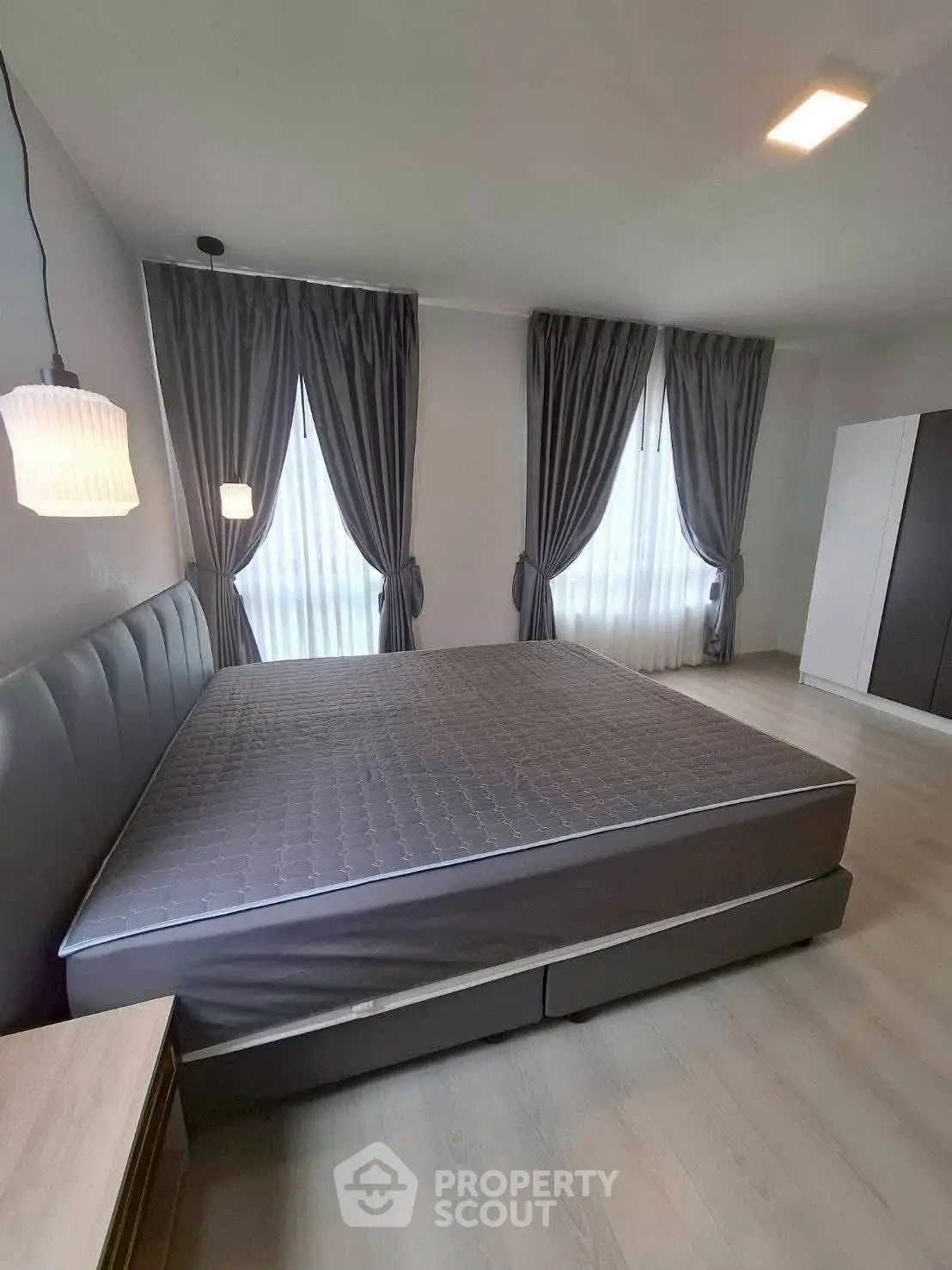 Spacious bedroom with elegant gray curtains and modern lighting