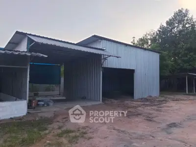 Spacious industrial warehouse with metal siding and open garage, ideal for storage or workshop use.