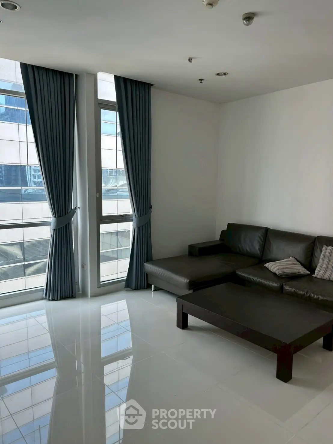 Modern living room with sleek leather sofa and floor-to-ceiling windows.
