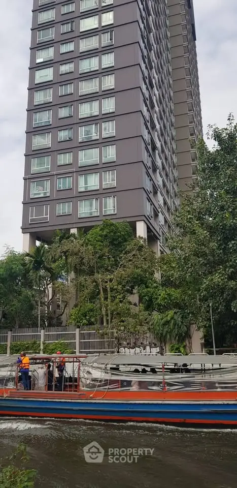 Modern high-rise building with lush greenery and waterway view, perfect for urban living.