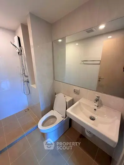 Modern bathroom with sleek fixtures and spacious shower area in a contemporary apartment.