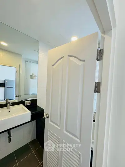 Modern bathroom with sleek sink and large mirror in contemporary apartment.