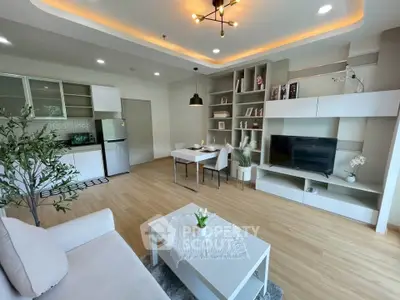 Modern open-plan living room with stylish decor and kitchen area, featuring sleek furniture and ambient lighting.