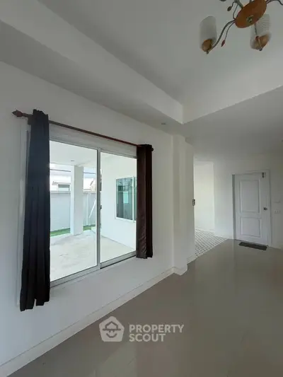 Spacious modern interior with large window and sleek flooring, perfect for natural light lovers.