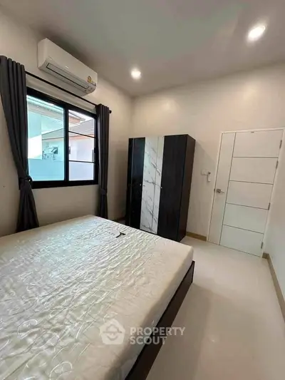 Modern bedroom with sleek design, featuring a large bed, wardrobe, and air conditioning.