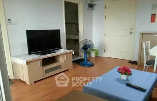 Cozy living room with TV and fan, featuring wooden flooring and modern decor.